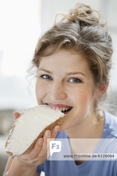Portrait of a woman eating toast with cream spread on it