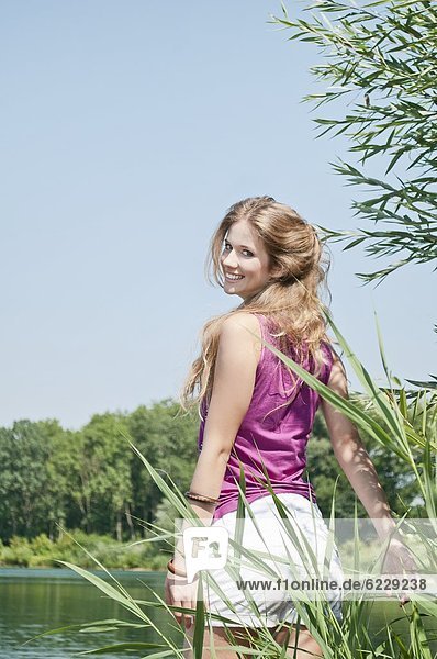 Blonde junge Frau an einem See