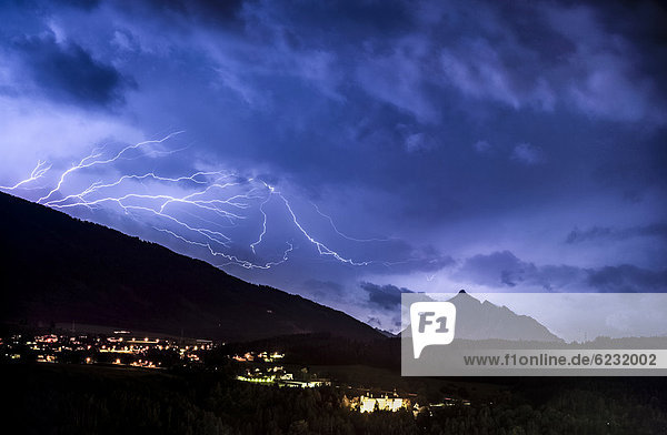Bedrohliche Wolkenstimmung und Blitze aus einer Gewitterzelle über dem Stubaital bei Innsbruck  hinten Serles und Orte Aldrans und Lans  Nachtaufnahme  Innsbruck  Tirol  Österreich  Europa