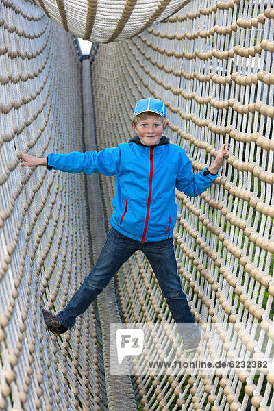 Boy  8  standing in a tunnel made from ropes
