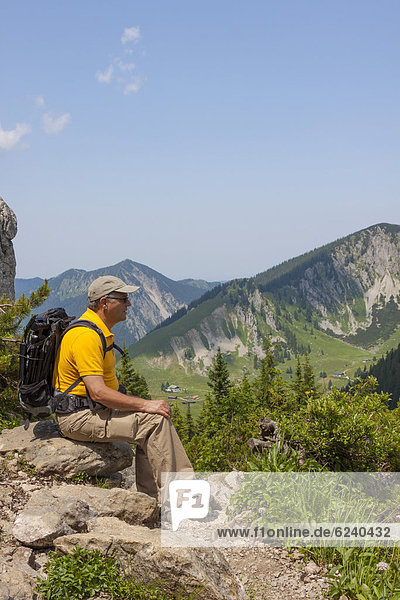 Hiker  56 years  sitting on rocks enjoying the view  Taubenstein near Spitzingsee lake  Mangfall Mountains  Alps  Bavaria  Germany  Europe