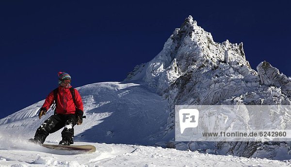 A snowboarder riding powder snow off the top of the famous Grand Montets ski area  high above Argentiere  Chamonix Valley  Haute Savoie  French Alps  France  Europe