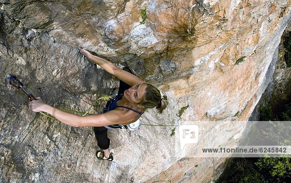 A climber makes her way up a steep and difficult route on the limestone cliffs in the Aveyron region  near Millau and Toulouse  south west France  Europe