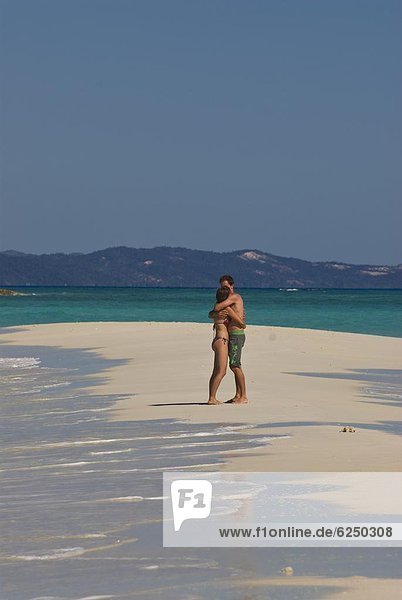 Happy couple on their honeymoon at the beautiful beach of Nosy Iranja near Nosy Be  Madagascar  Indian Ocean  Africa
