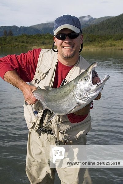 Fisherman holding a Silver (Coho) salmon (Oncorhynchus kisutch)  Coghill Lake  Alaska  United States of America  North America