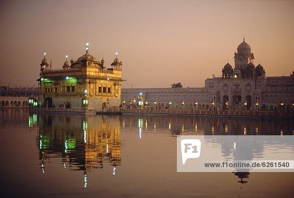 Dusk over the Holy Pool of Nectar looking towards the clocktower and the Golden Temple  Sikh holy place  Amritsar  Punjab State  India  Asia