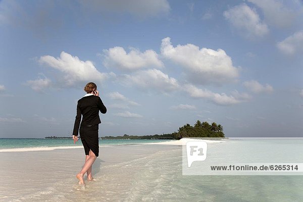 Woman with cell phone on a tropical beach  Kuramathi Island  Ari Atoll  Maldives  Indian Ocean  Asia