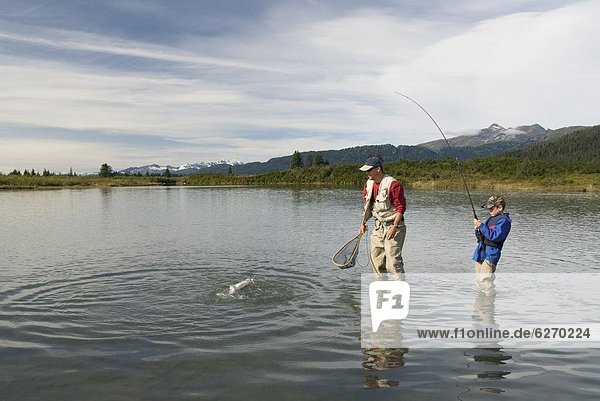 Boy catching a Silver (Coho) salmon (Oncorhynchus kisutch) with dad's help  Coghill Lake  Alaska  United States of America  North America
