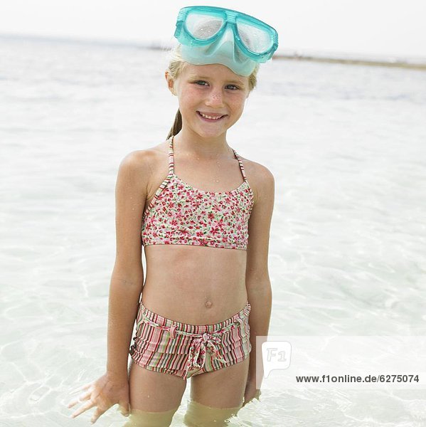 Girl (6-8) on beach wearing swimming mask