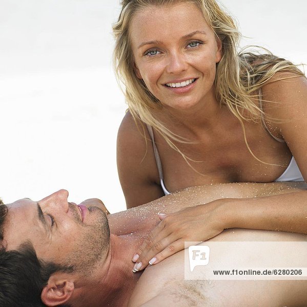 Couple lying together on beach  smiling