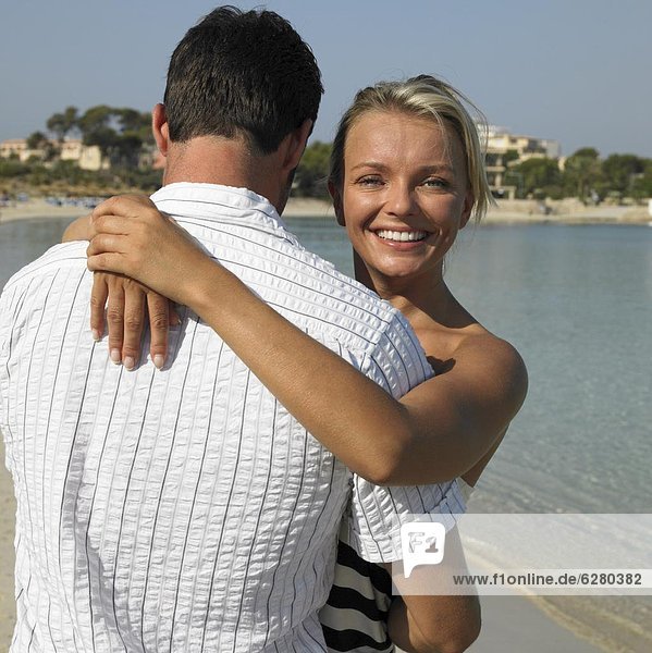 Paar umarmen am Strand  lächelnd