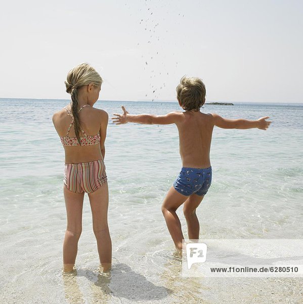 Boy and girl on beach playing in the water
