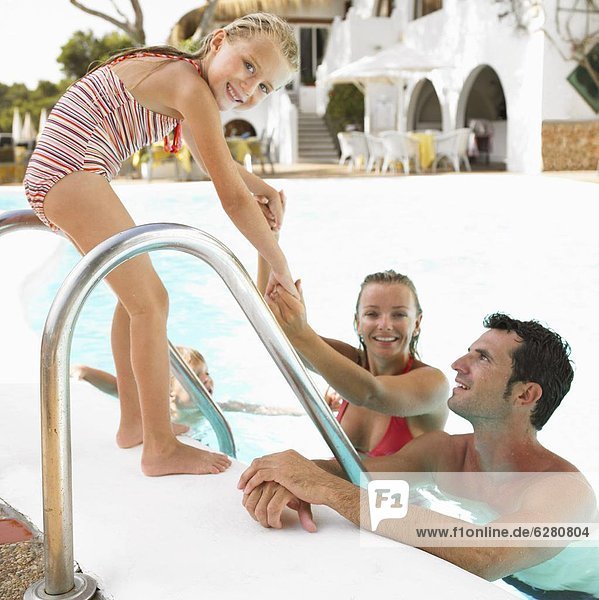 Parents and daughter (6-8) by swimming pool