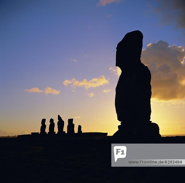 Silhouette of Ahu Tahai in foreground and behind the five moai (statues) of Ahu Vai Uri  Easter Island  Chile