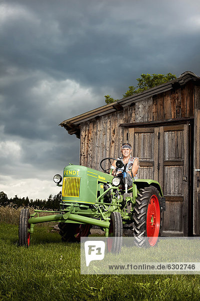 Man with a prosthetic leg driving a vintage tractor