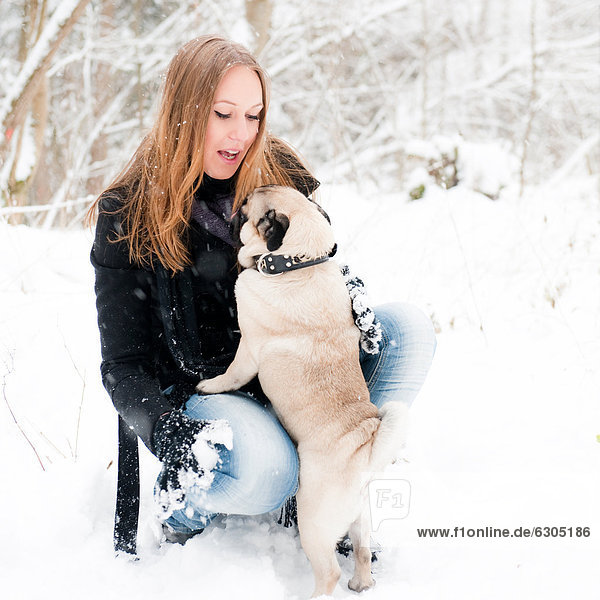 Young woman with pug dog in snow