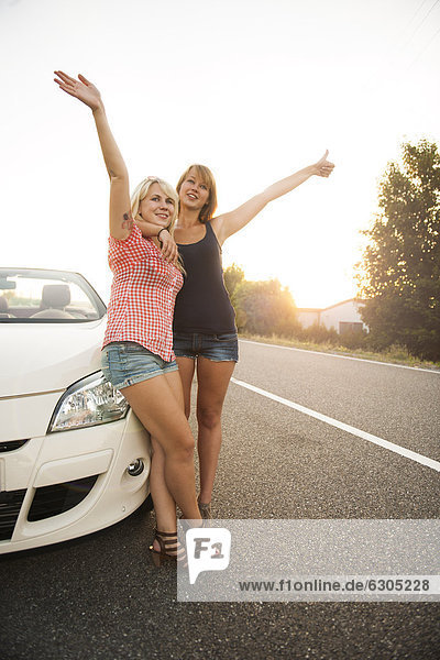 Zwei Freundinnen stehen an einem Cabrio