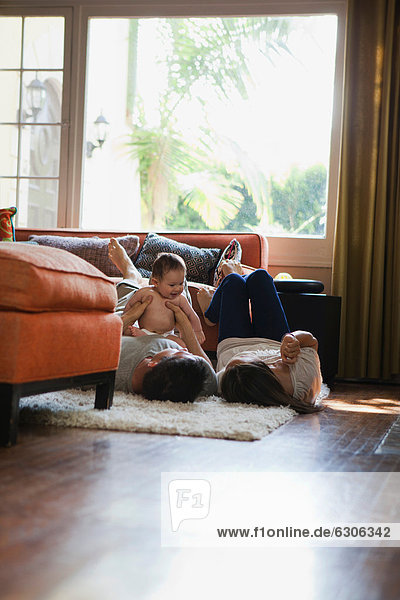Mother and father lying on floor holding baby boy