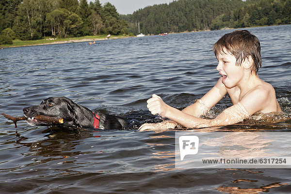 Boy playing with his hunting dog in a lake