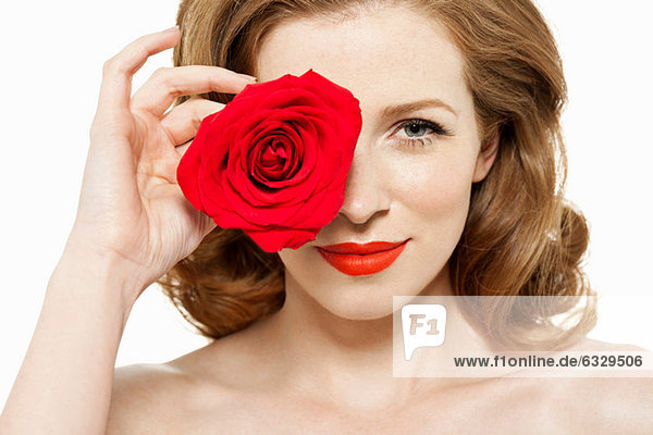 Frau bedeckt Auge mit roter Rose