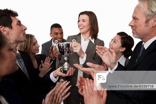 Businesswoman receiving trophy  colleagues clapping