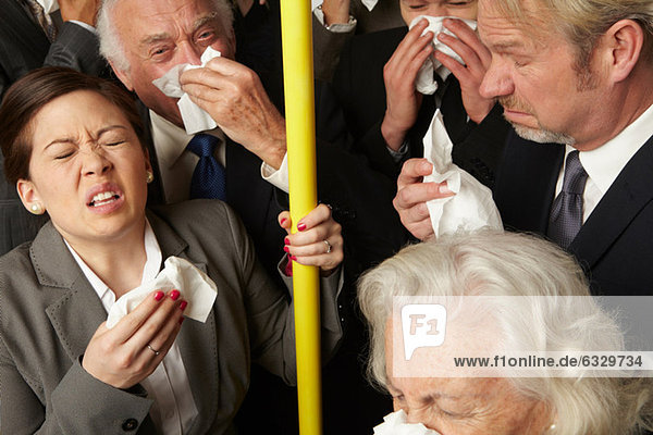 Businesspeople sneezing on subway train