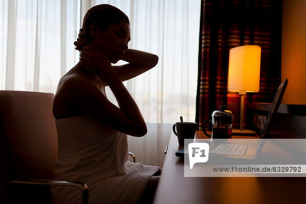 Junge Frau sitzt am Laptop im Hotelzimmer