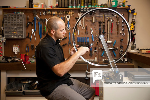 Man fixing bicycle rim in workshop