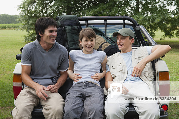 Friends sitting in back of pick-up truck  laughing