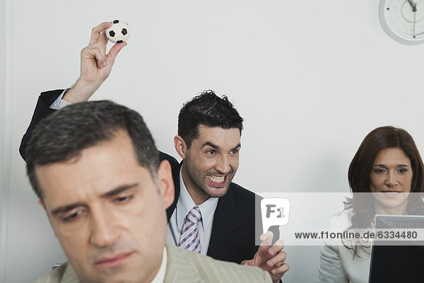 Business people in office  young businessman throwing mini soccer ball