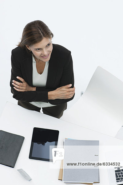 Businesswoman standing by desk with arms folding  high angle view