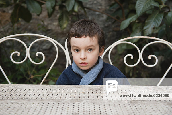 Boy sitting at table outdoors  portrait