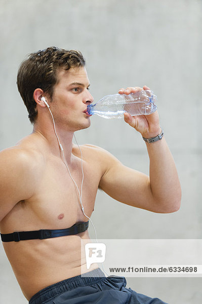 Barechested young man drinking bottled water