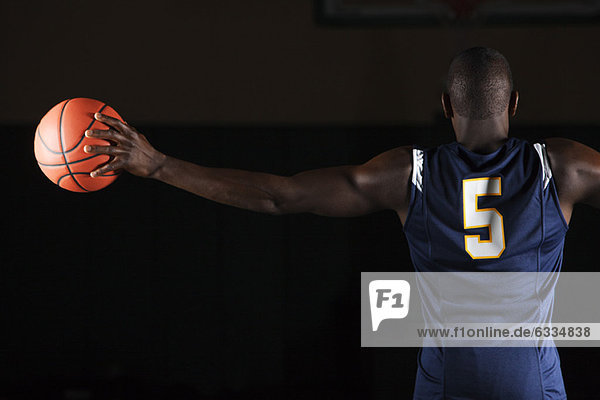 Basketball player holding basketball in hand  rear view