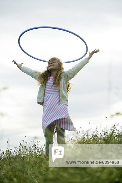 Girl throwing plastic hoop in air