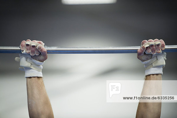 Gymnast's arms gripping horizontal bar  cropped