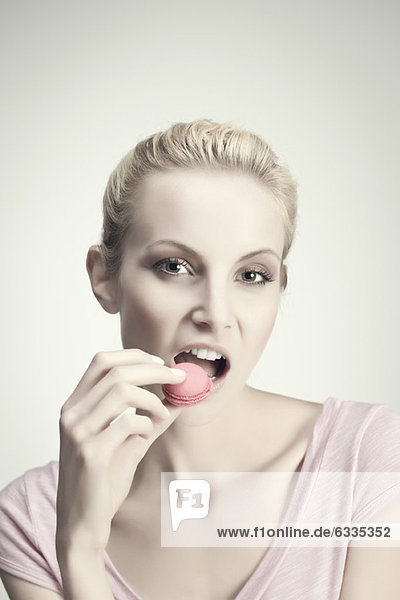 Young woman eating macaroon  portrait