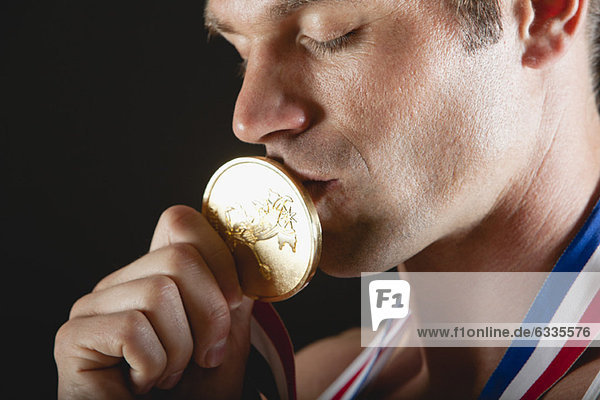 Athlet küsst Goldmedaille