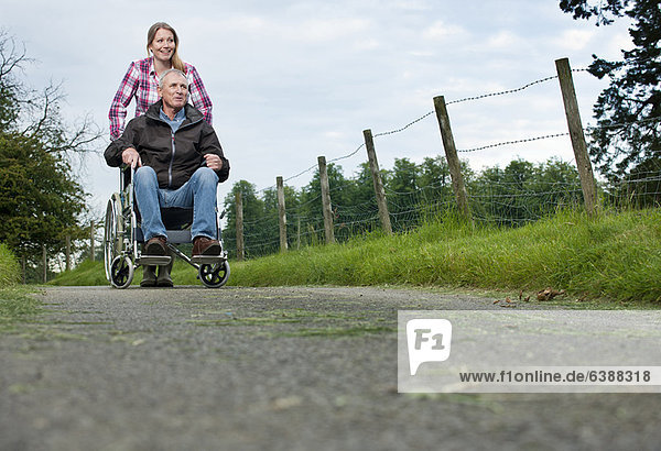 Frau schiebt Vater im Rollstuhl