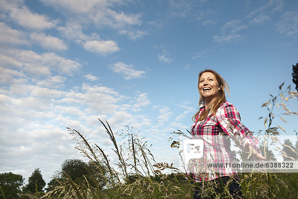 Lächelnde Frau im hohen Gras unterwegs