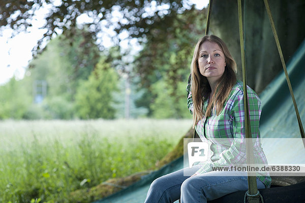 Frau sitzend in Reifenschaukel im Freien