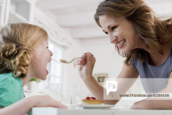 Frau füttert Tochterfrühstück