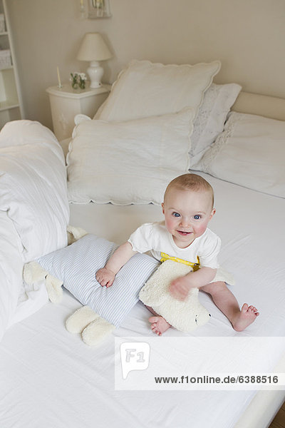 Smiling baby sitting on bed