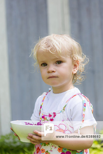Girl holding flower in bowl outdoors