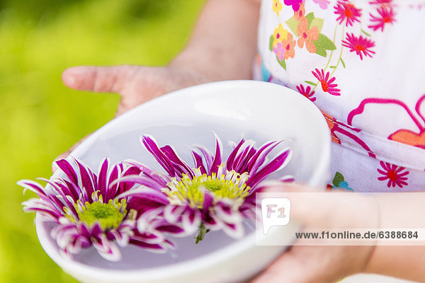 Girl holding flowers in bowl outdoors