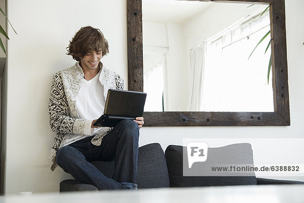 Teenager Junge mit Laptop auf dem Sofa
