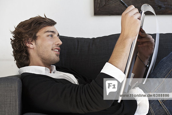 Teenager-Junge macht sich Notizen auf dem Sofa