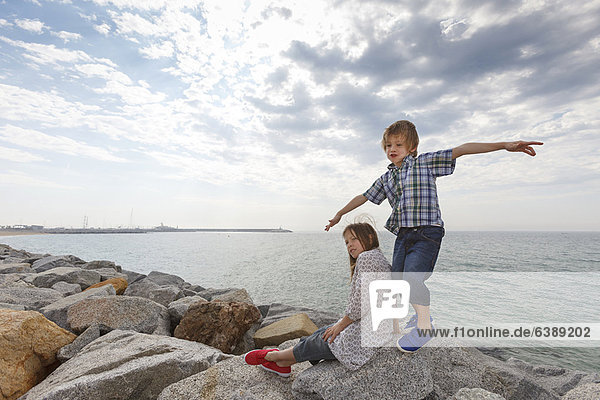 Kinder spielen auf Felsen am Strand