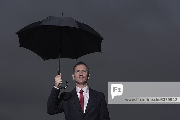 Geschäftsmann steht unter dem Schirm
