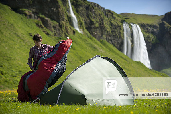 Frau mit Schlafsack und Zelt  Wasserfall Seljalandsfoss am Fluss Seljalands·  Ringstraße  Su_urland  Süd-Island  Island  Europa